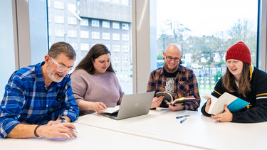 Mature students studying together using laptop and textbooks 