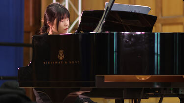 Student sat playing a grand piano