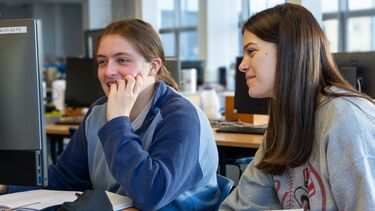 Two students in a physics lab session looking at a computer