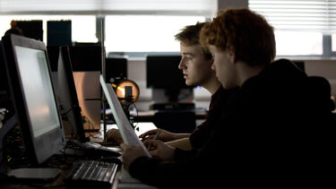 Two students in a physics lab session looking at a computer