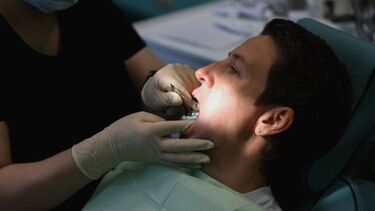A dentist examines a patient's mouth