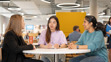 Three postgraduate students sat chatting in a cafe on the University of Sheffield campus