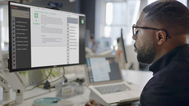 A man looking at a computer in an open plan office