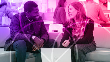 Two people talking over a laptop 