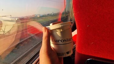 Eurostar - window image of journey Amsterdam to Brussels - Eurostar branded coffee cup being held in one hand shown