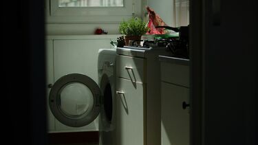 Sunlight lights up part of a kitchen where a circular washing machine door is open