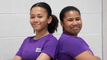 Two girls stood back to back 