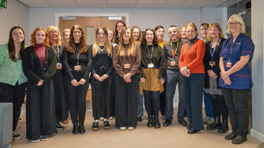 A staged group photo of 18 people in an office building