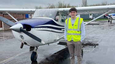 Student stands in front of a small aeroplane 