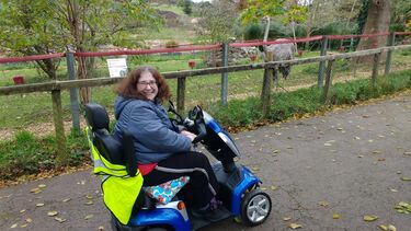 Amanda on an electric scooter in a park with wildlife