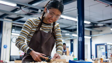 Architecture student using tools for woodworking in print and make workshop