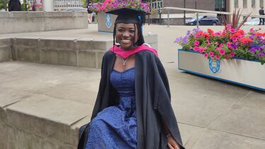 A woman sat outside the Arts Tower wearing a graduation outfit