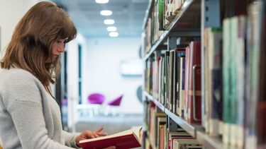 A student browses the shelves in the library