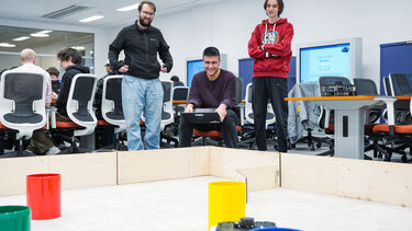 3 students looking at robot arena