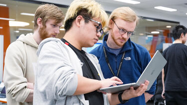 3 students look at laptop screen