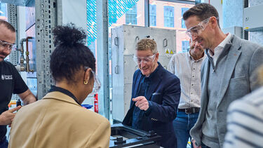 People standing around a table of equipment wearing protective glasses 