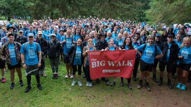 A wide-angle shot of a large gathering of walkers at the start of the Big Walk 2025, holding up a Big Walk banner