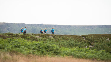 Five Big Walk participants crossing moorland below Stanage Edge