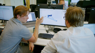 Student pointing to an image on a screen speaking with an engineer