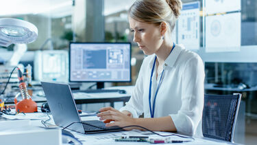 A computer scientist working on her laptop in a lab