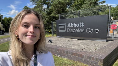smiling student standing by the Abbott Diabetes Care sign