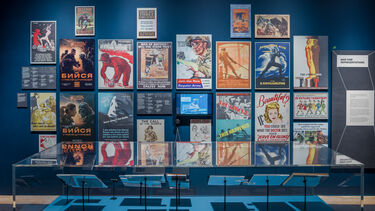 An exhibition space featuring a wall of war posters