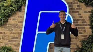 Student, thumbs up, standing in front of the PayPal logo
