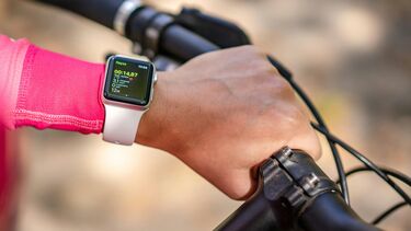 Cyclist's arm wearing a smart watch grips the handlebars