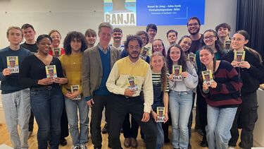A group of students holding books and smiling 