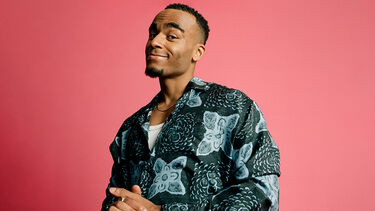 Munya Chawawa smiling in a patterned shirt against a plain pink background