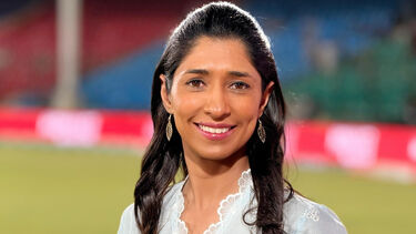 Urooj Mumtaz Khan smiling on a cricket field and wearing a long white shirt