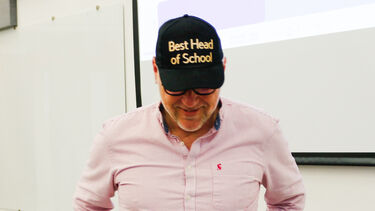 A person is wearing a hat which says Best Head of School