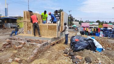 Four people working on building the walls and insulation of the sustainable cold room 