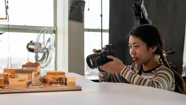 Architecture student photographing model in media unit 