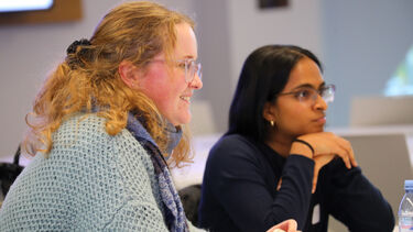 Two women sat at desk smiling 