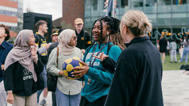 People stood chatting, one person is holding a football