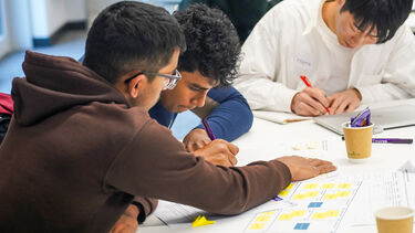 3 students working on desk together 