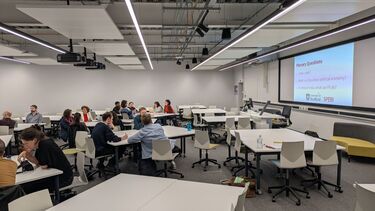 participants sit around tables discussions questions displayed on the board