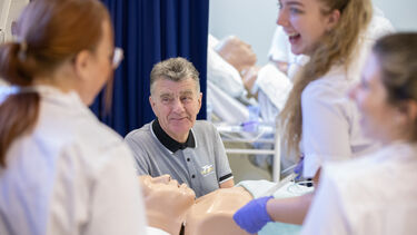 A volunteer patient with a group of student nurses