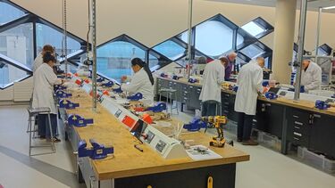 Students wearing white lab coats working in an engineering lab