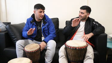 Two males drumming on sofa 