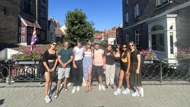 Nine young people in summer gear posing on a bridge in Gent