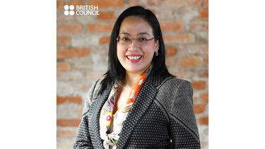 profile headshot of Mary-Ann Ooi Suan Kim, smiling in a business suit against the backdrop of an indoor brick wall