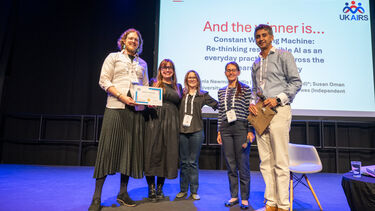 Academics from the University of Sheffield's Centre for Machine Intelligence being presented with an award on stage at the UKAIRS symposium