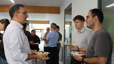 Three men are chatting while holding plates of food