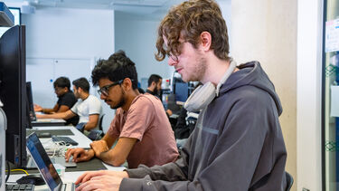 Two students are coding in the lab