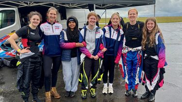 Group of women smiling at at camera on race track 