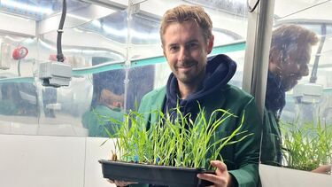 Dr Robert Caine standing holding grass