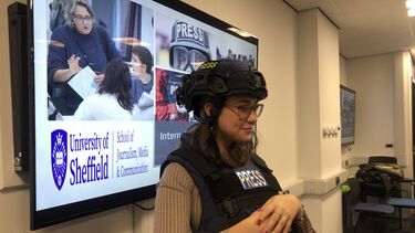 Journalism student wearing protective vest and press helmet as worn by war correspondents.