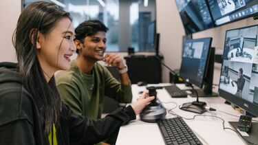 Two students smiling and looking at computer screens